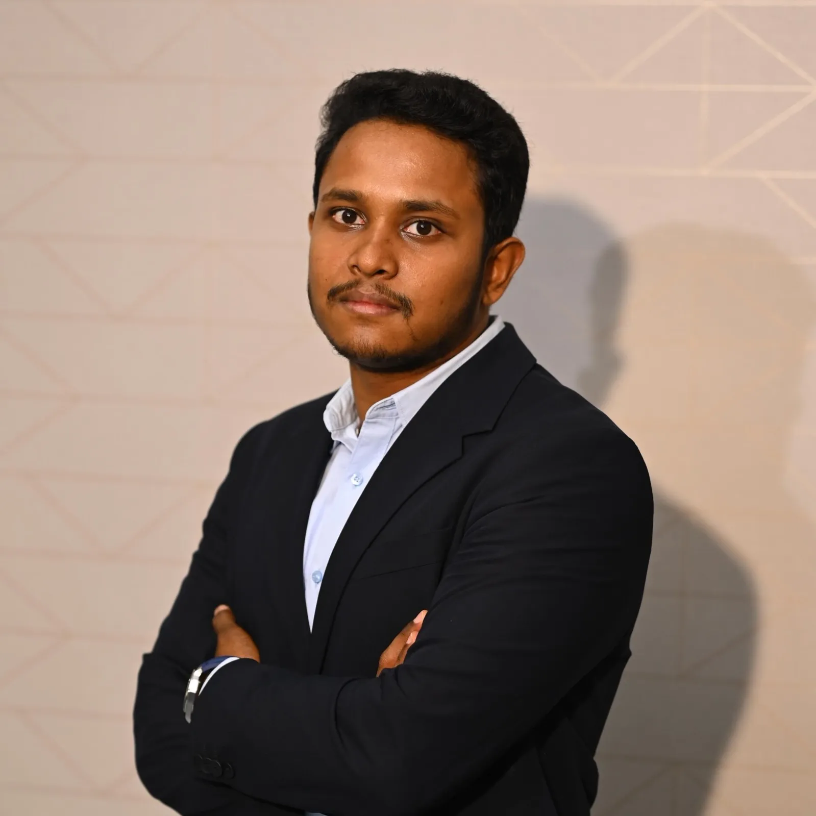 Professional portrait of K. Sai Rohith, Managing Director of Ramachandra College of Engineering, standing with folded arms against a geometric light‑colored background.